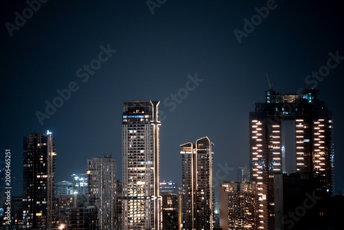 Modern highrise multi storey skyscrapers at night with lights shining through showcasing growth of apartments, buildings, houses and shopping centers in cities like gurgaon, delhi, bangalore, hyderaba