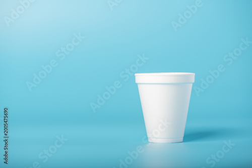 Bild auf Leinwand White cup, a white styrofoam cup on a blue background, selective focus