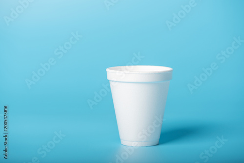 Foto White cup, a white styrofoam cup on a blue background, selective focus