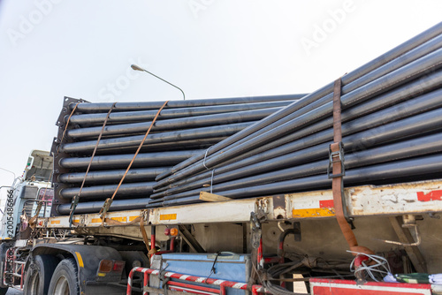 Fotografi Heavy black steel pipe load on flatbed truck for industrial construction transpo