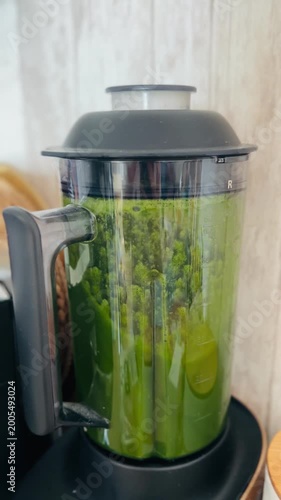 Green smoothie blender filled with fresh vegetables on wooden surface  