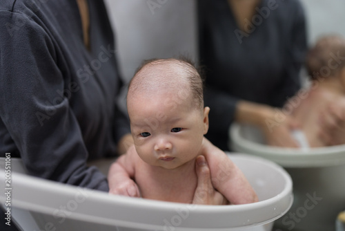 Obraz na plátně Mother washing newborn baby carefully during bath time at home