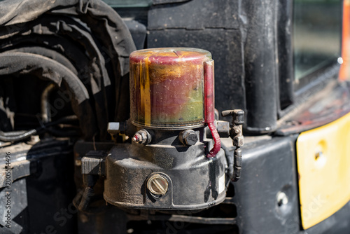 Automated lubrication system reservoir filled with red grease on a heavy duty excavator, illustrating industrial machinery maintenance, mechanical engineering and hardware service