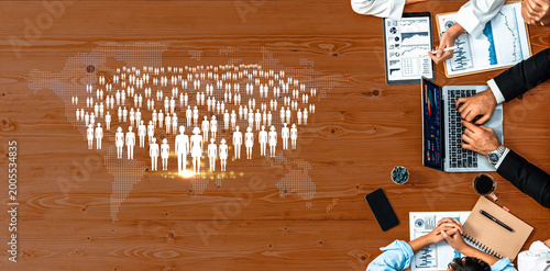 Modern Business Meeting with Diverse Professionals Analyzing Data and Trends Over Digital Graphics of People and World Map on a Wooden Table Quark.