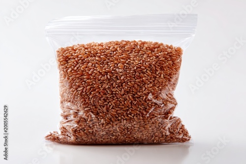 Bag of red rice in clear plastic packaging on white background