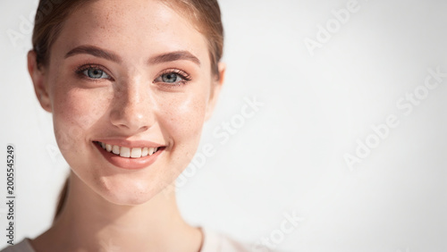 Portrait of beautiful young woman with freckles, natural skin and soft light beauty concept
