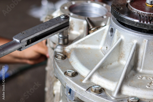 Quadro su tela ​A professional technician uses a precision torque wrench to tighten bolts on a heavy-duty aluminum transmission casing during a mechanical assembly process
