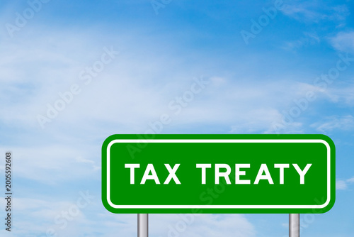 Green color transportation sign with word tax treaty on blue sky with white cloud background