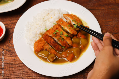 Hand lifts chopsticks over curry and rice
