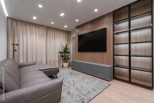 Billede på lærred Modern living room interior with wooden accent wall, wall mounted TV, minimalist furniture and soft lighting, contemporary apartment design with neutral tones and elegant decor