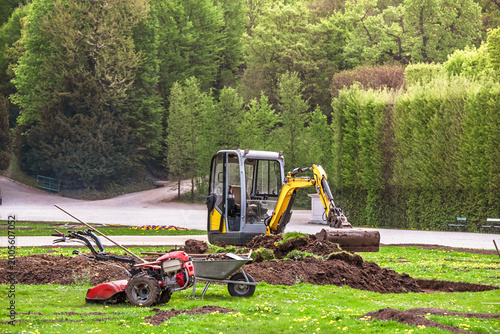 Landscaping works with mini excavator and garden tiller preparing soil 