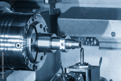 Advanced multi-tasking CNC machine producing high precision metal shaft parts in a blue-toned industrial scene.