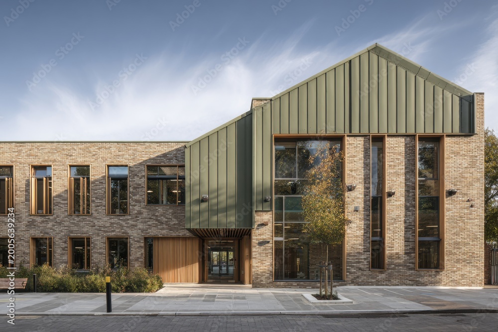 Obraz premium Modern building design showcasing brick and metal structure with large windows on a clear day in an urban setting, emphasizing contemporary architecture and functional space
