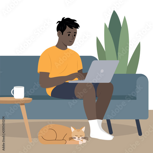 A black man sits on the couch and works on his laptop remotely, while his cat lies on the floor