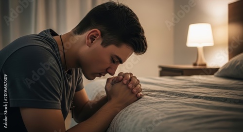 young man praying on bed with hands clasped