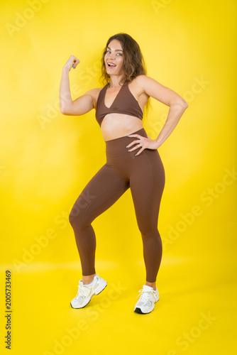 Obraz na plátně Woman confidently flexing bicep showing strength and fitness