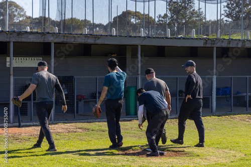 Canvastavla Five male players bending picking up ball on mound, holding gloves and bat prepa