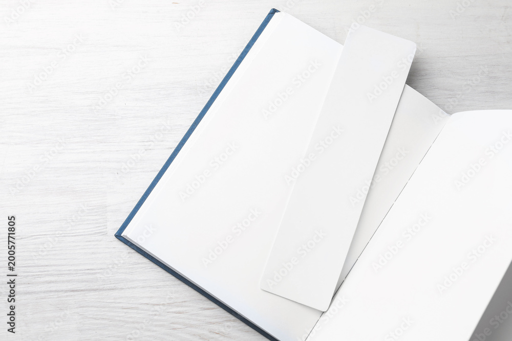 Obraz premium Book with white bookmark on light wooden table, top view. Space for text