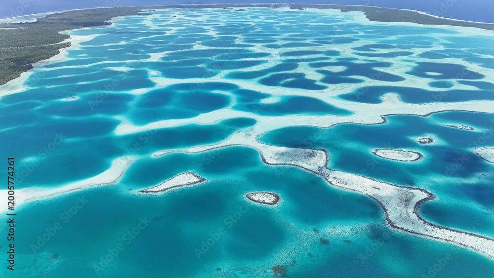 Fototapeta premium Aerial drone shot of turquoise lagoon in French Polynesia with tropical island, clear blue water and luxury travel destination