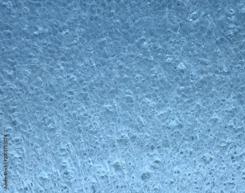 Macro shot of blue porous foam or sponge texture showing small holes and uneven surface, ideal as an abstract background representing material structure, cleaning concept, or industrial design