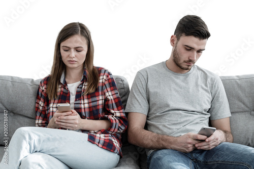 Young couple showing disinterest in each other after quarrel, each one using their phones