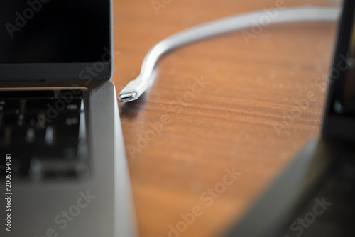 USB C Cable Connected to Laptop on Wooden Desk