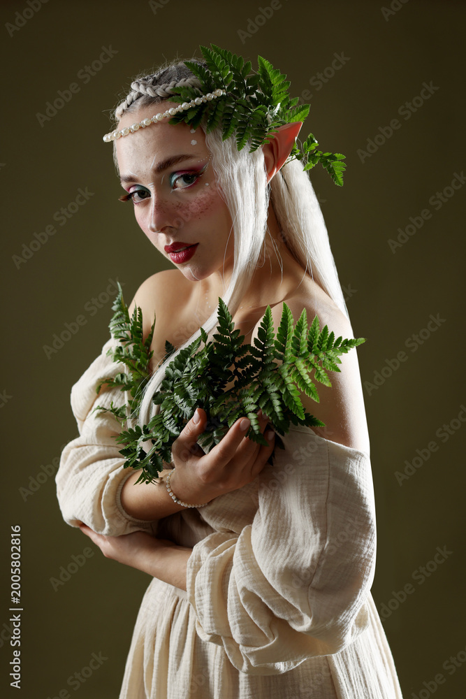 Fototapeta premium Beautiful elf girl with floral decor on dark olive background