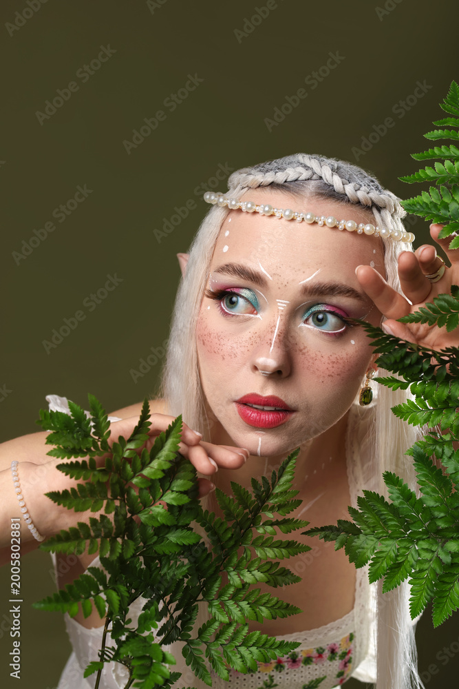 Fototapeta premium Beautiful elf girl with floral decor on dark olive background