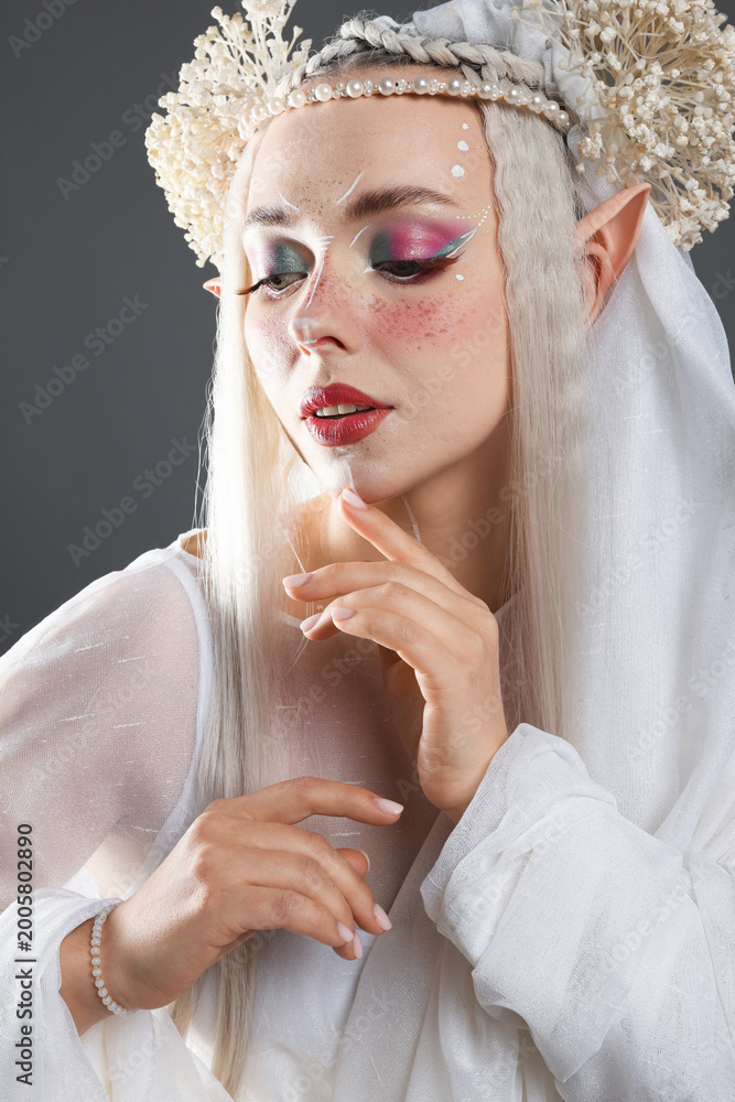 Obraz premium Beautiful girl dressed as elf on grey background