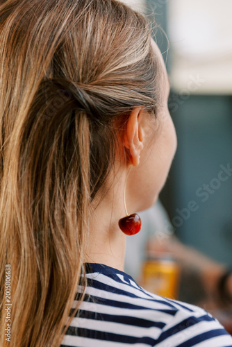 Woman wearing a cherry earring and striped shirt from behind