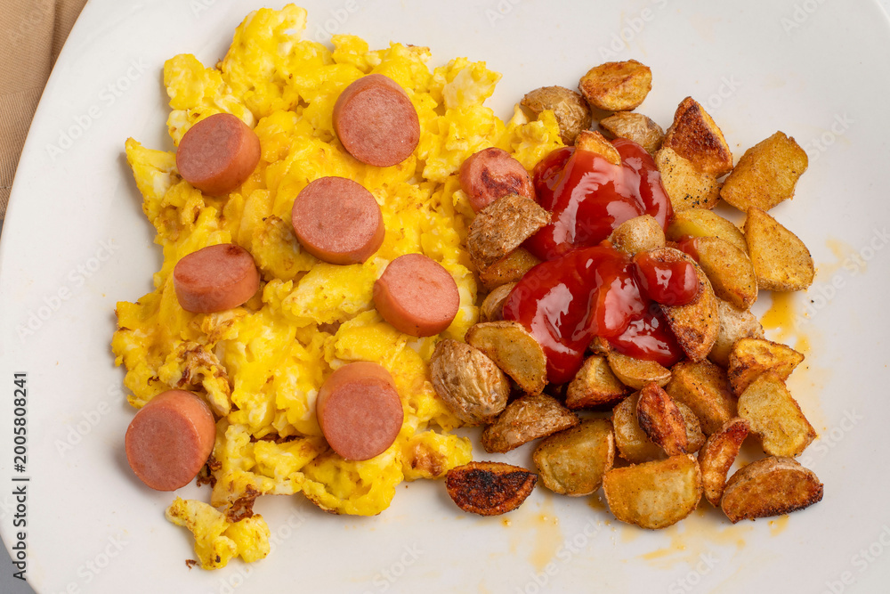 Fototapeta premium scramble eggs top with hot dogs and home fries