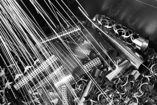 Cut metal parts in a pile, sparks from a metal cutting laser machine fall on them as an industrial concept background
