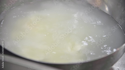 Stracciatella cheese preparation process in stainless steel bowl with water