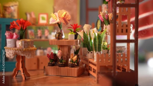A cozy interior view of a handmade miniature flower shop diorama. Features tiny furniture, paper plants, and warm lighting, showcasing the intricate details of a creative DIY dollhouse room box.