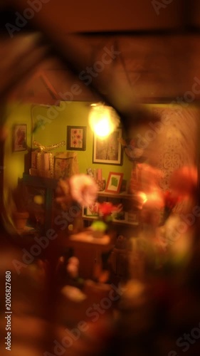A cozy interior view of a handmade miniature flower shop diorama. Features tiny furniture, paper plants, and warm lighting, showcasing the intricate details of a creative DIY dollhouse room box.