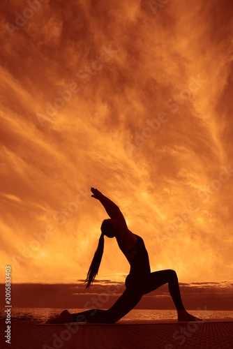 Anjaneyasana  New Moon Pose Woman stretching outdoors, fit female doing Crescent High Lunge pose,  Eight Point Moon at sunset, yoga exercise in nature, side view full length Evening sky background