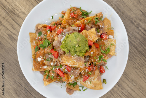Foto Overhead view of hearty plate of nachos smothered in guacamole, beans, and feta