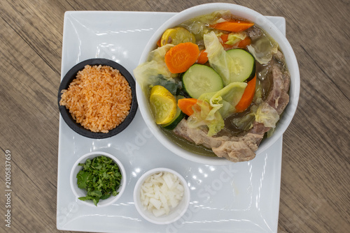 Overhead view of hearty bowl of beef soup loaded with chopped vegetables, rice, and beans to satisfy that urge for a Mexican food meal
