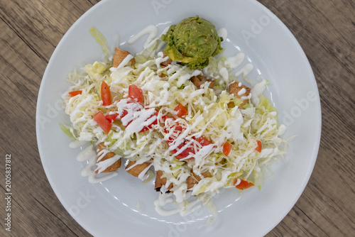 Overhead view of hearty plate of flautas smothered in guacamole, sour cream, and cabbage to satisfy that urge for a Mexican food meal