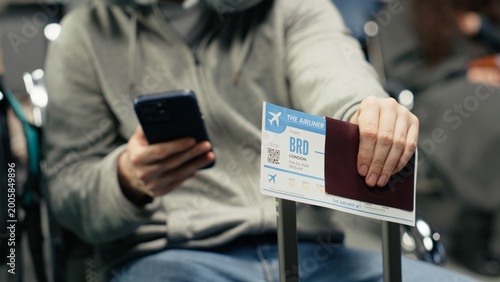 Waiting for plane arrival, boarding pass and man in airport checking flight itinerary on smartphone. Doing trip planning, passport document and passenger using phone, camera A