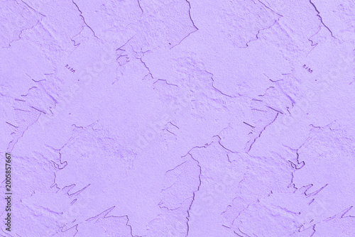 A soft lavender stucco wall shows a rough and cracked textured surface.