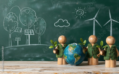 Three wooden figures hold plants standing before a chalkboard with