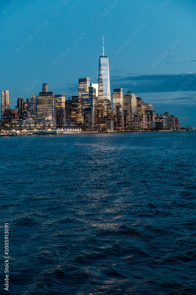 Fototapeta premium One World Trade Center and Lower Manhattan skyline night. Long shot of One World Trade Center and financial district skyline from Hudson River at twilight.