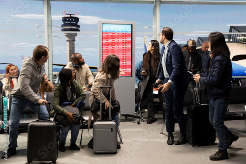 Photography Worried about disruption, delayed flight and passengers in airport reacting to red alert on airline screen