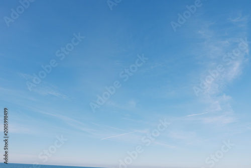 Billede på lærred Clear blue sky over calm ocean with distant horizon and light wispy clouds, tran
