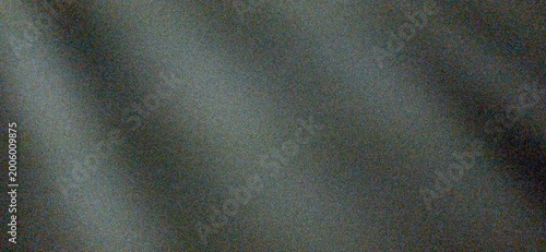 Foto A dark, out-of-focus abstract background with significant digital noise, showing a soft diagonal light grey glow against a deep charcoal base