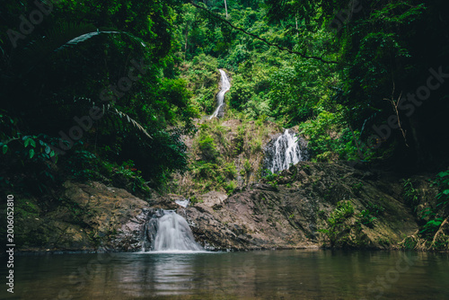 Foto Tropical jungle waterfall flowing through dense rainforest with emerald natural