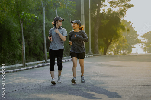 Two asian female friends or sisters doing sport activities on the park. Running, stretching, jogging in the morning. Healthy lifestyle concept.
