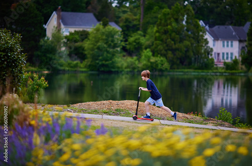 Young Boy, Kid Scootering Along Scenic Lakeside Path – Active Childhood in a Quiet Neighborhood