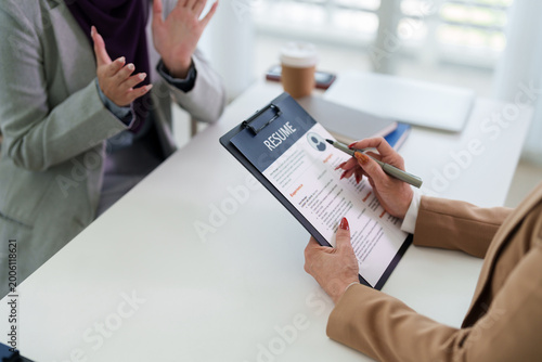 professional job interview manager reviewing applicant resume document hiring recruitment meeting candidate hands evaluating cv paper office desk career